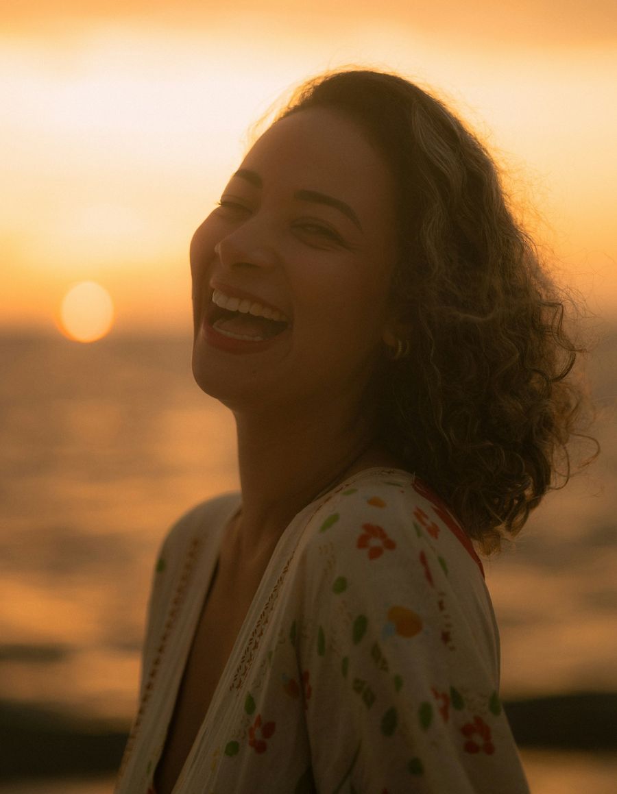Femme souriante au coucher du soleil : retrouver le goût de vivre grâce à une thérapie par le ressenti à Lyon